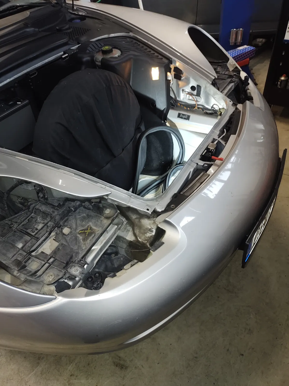 Свален фар и отворен преден багажник на сребристо Porsche